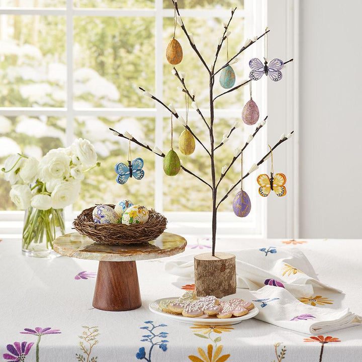 Quilled butterflies on a twig tree on an Easter themed tablecloth. 