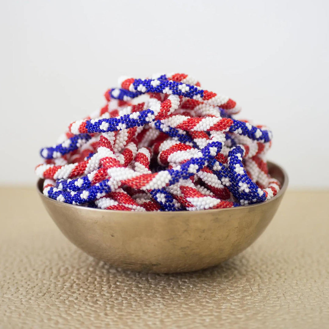 Beaded roll-on bracelets with a stars and stripes pattern displayed in a bowl.