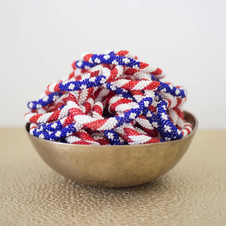 Beaded roll-on bracelets with a stars and stripes pattern displayed in a bowl.