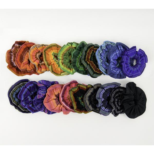 A collection of multicolored scrunchies arranged in a gradient of colors, with shades of purple, green, yellow, and black predominating.