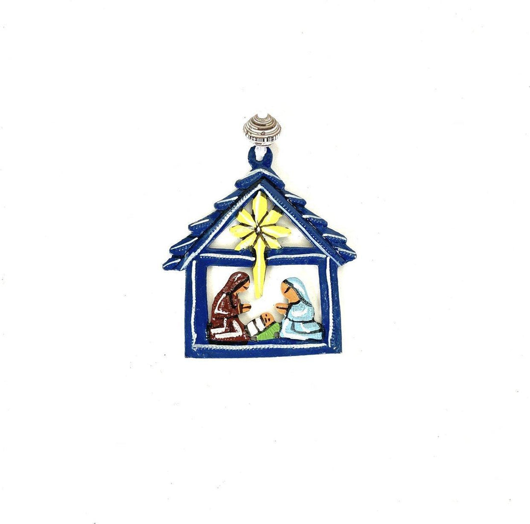 A blue metal nativity ornament on a white background. 
