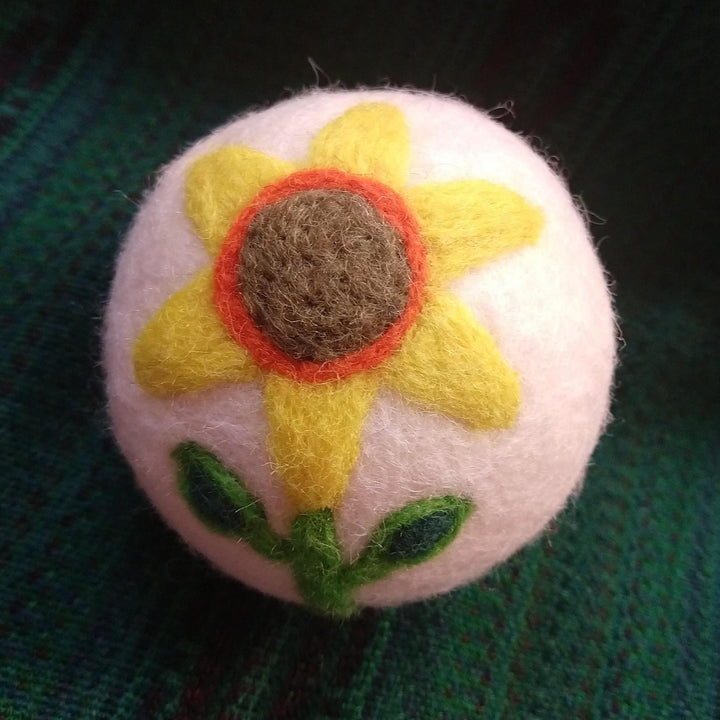 a sunflower dryer ball on a green knit backgroung
