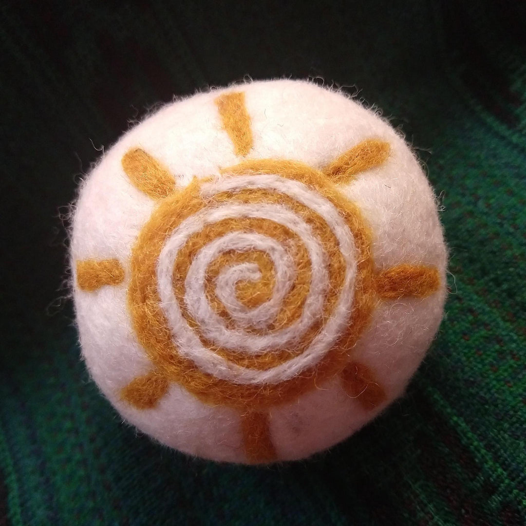 a sunflower dryer ball on a green knit background