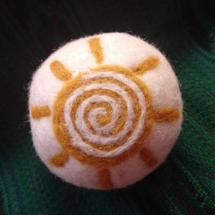a sunflower dryer ball on a green knit background