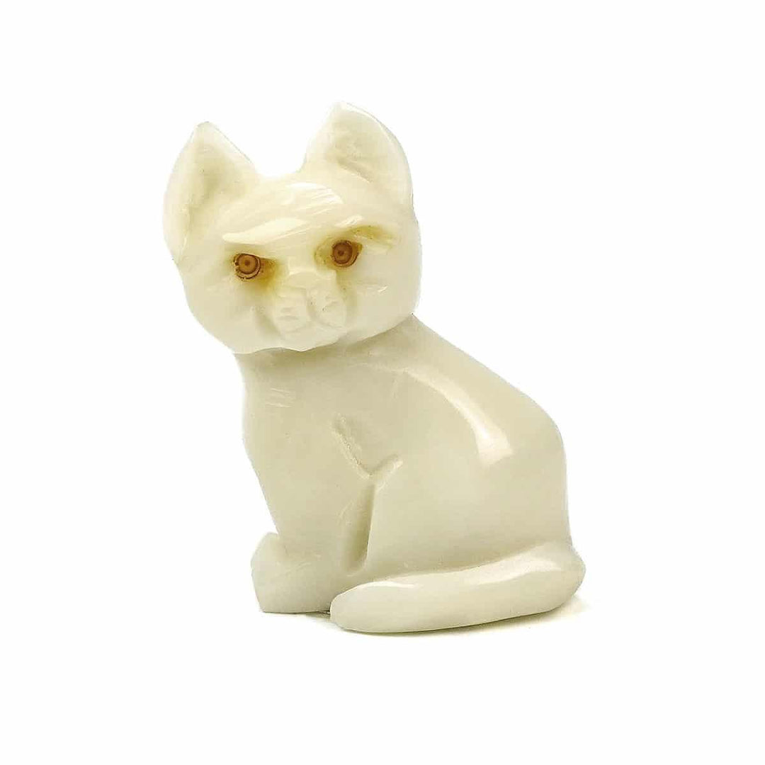 a hand carved tagua nut cat in a sitting position on a white background