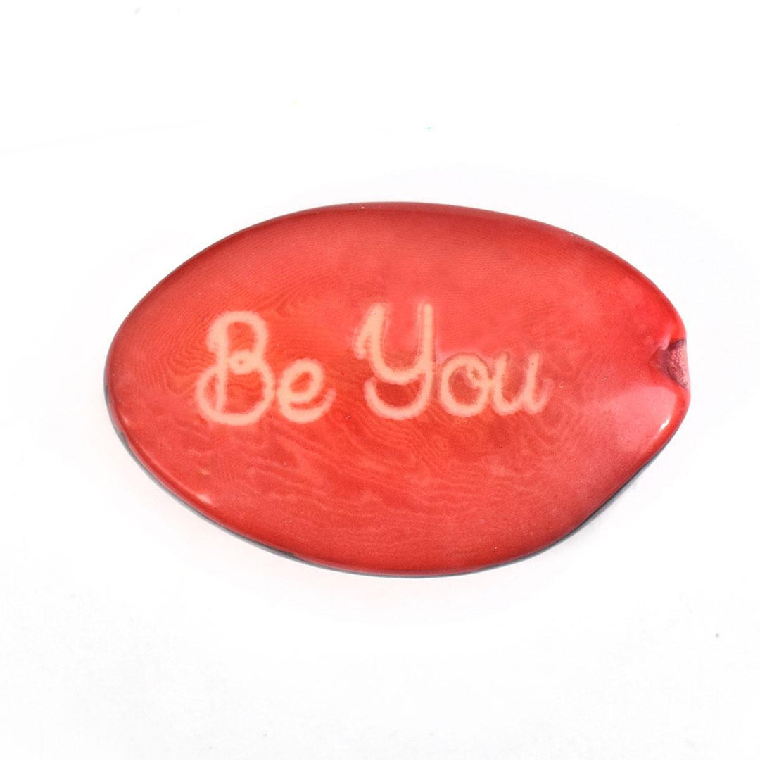 a coral tagua nut with the word 'be you'