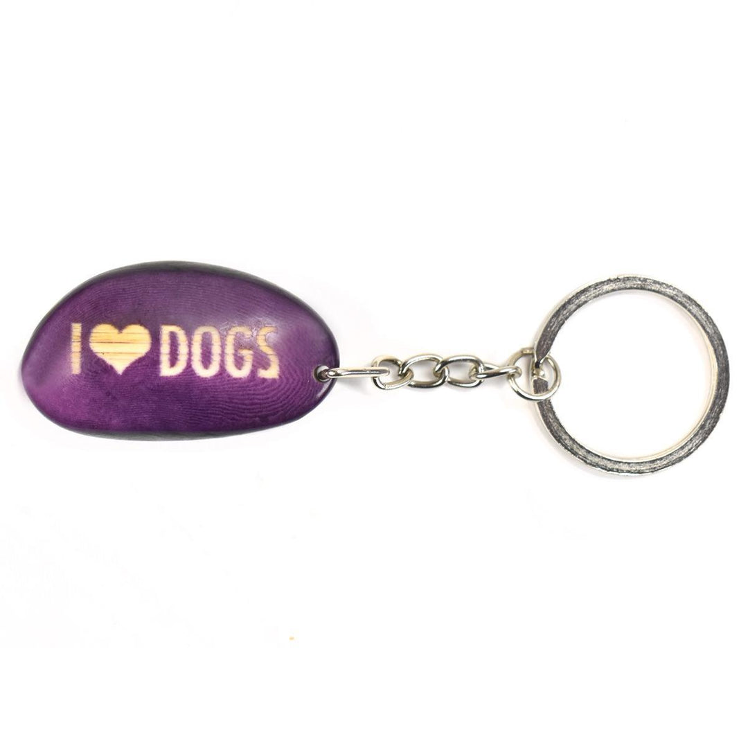 A purple tagua nut keychain with the word 'I heart dogs' engraved on it, attached to a metal keyring.