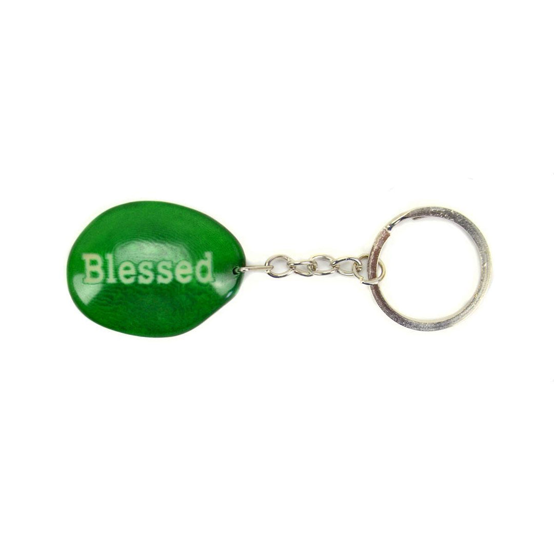 a green tagua keychain with the word 'blessed' engraved on it