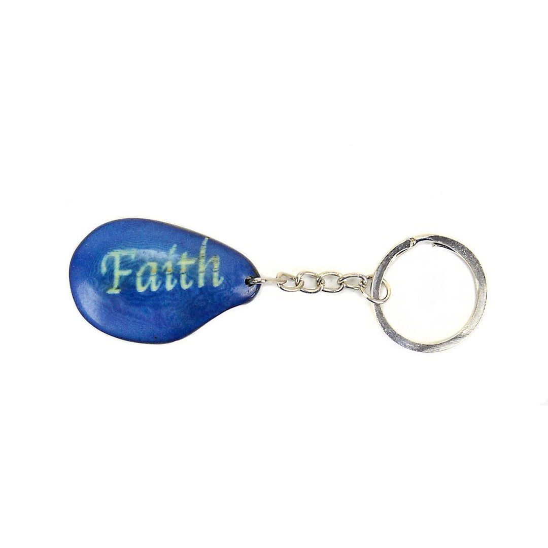 A blue tagua nut keychain with the word 'Faith' engraved on it, attached to a metal keyring.