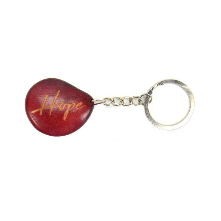 A red tagua nut keychain with the word 'hope' engraved on it, attached to a metal keyring.