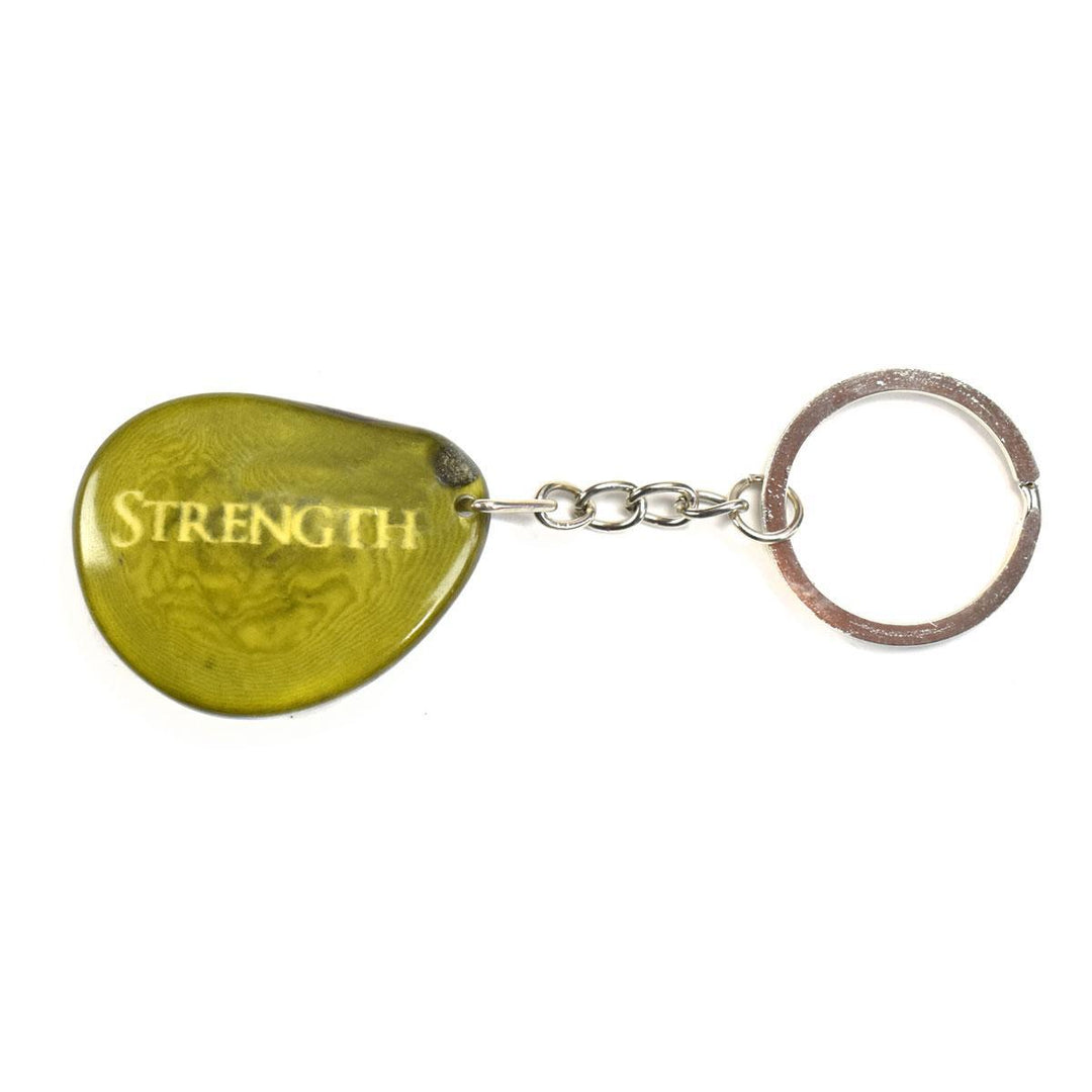 A green tagua nut keychain with the word 'Strength' engraved on it, attached to a metal keyring.