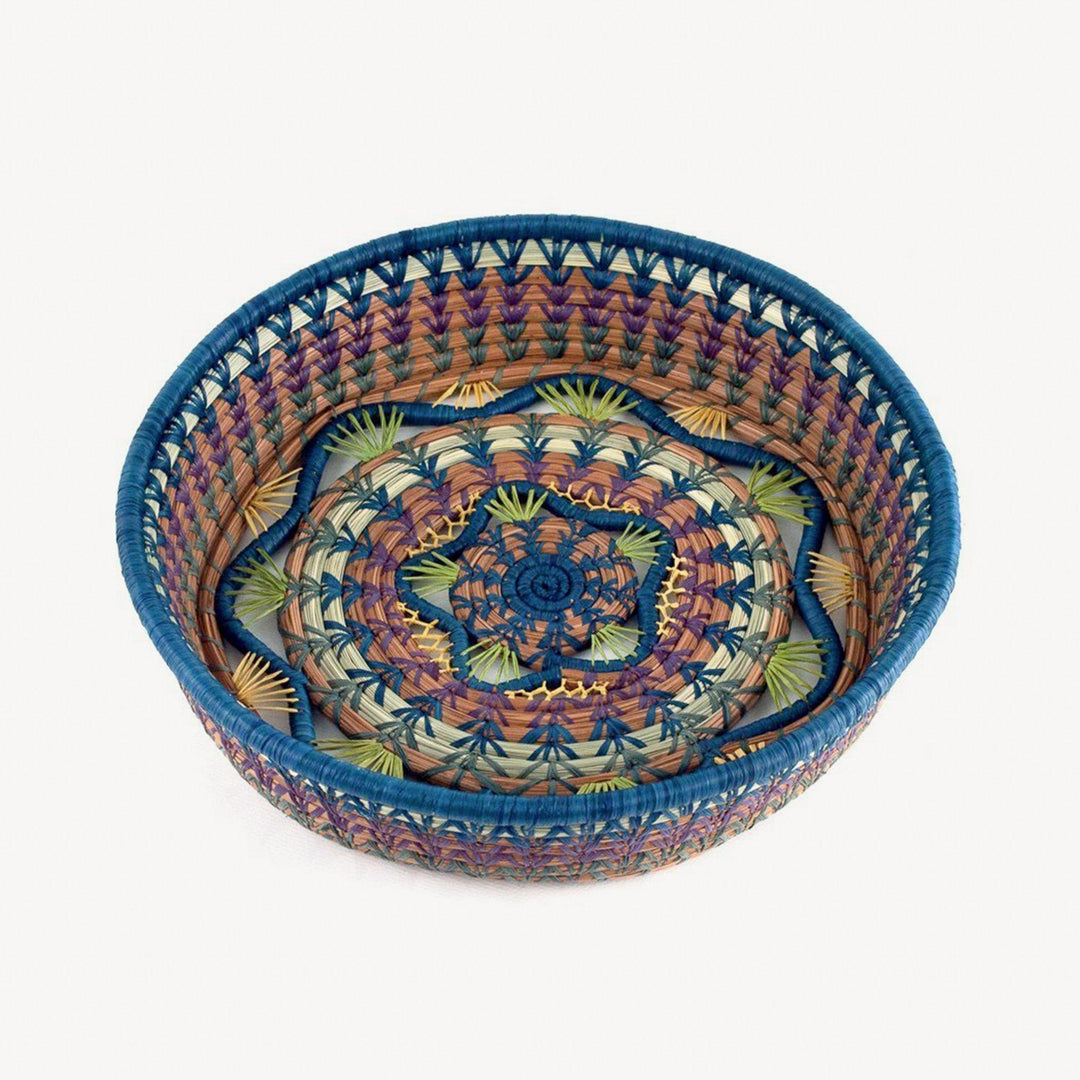 Handmade woven basket with colorful patterns on a white background.