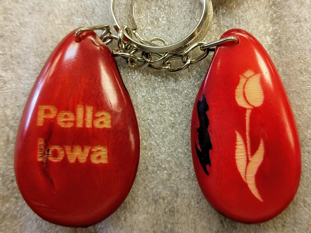 Two red tagua keychains with 'PELLA, IA' and a tulip design, attached to a metal chain.